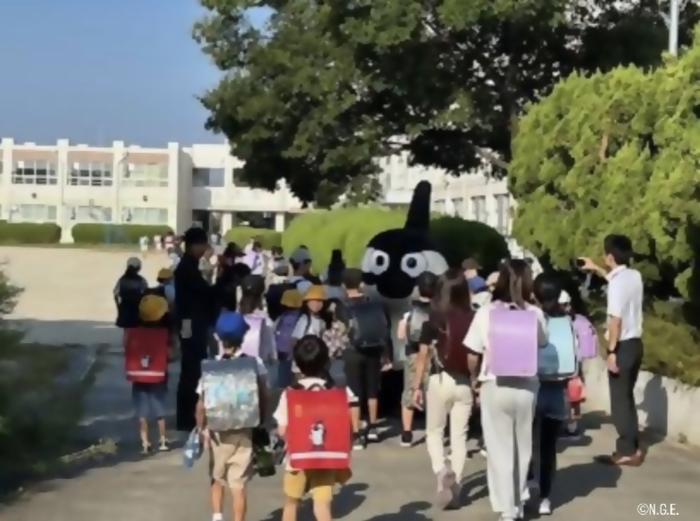 グランパスくんが小学校に訪問し朝の挨拶運動する様子