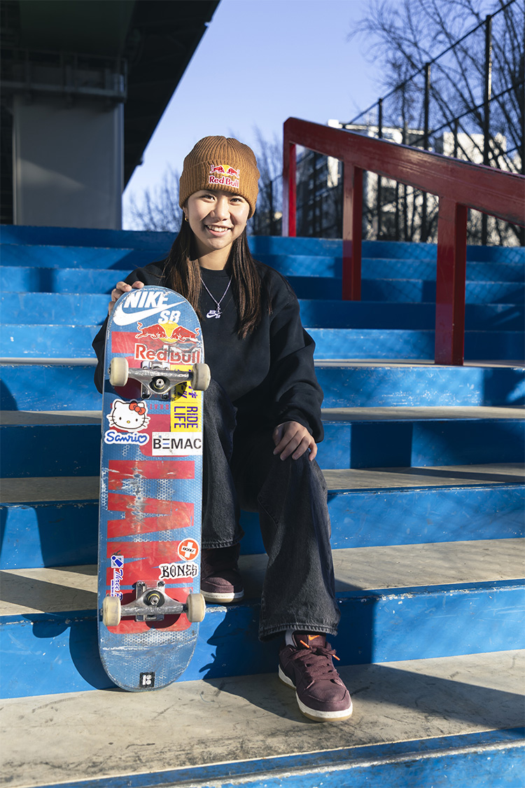 織田夢佳選手が階段に座り、スケートボードを立てている写真